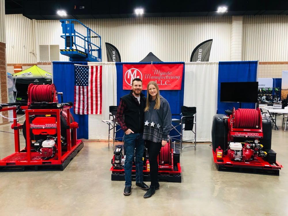 Andrew and Abigail Bell at a farm show booth with Minute Manufacturing fire skids